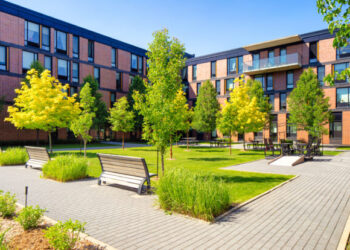 Panoramic view of an idyllic Montreal apartment complex with a landscaped courtyard in late Springtime on a clear sunny day.