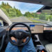 Driving down an empty highway in a high-tech autonomous Tesla vehicle. Young man drives along a scenic rural motorway hands-free in a modern self-steering car.