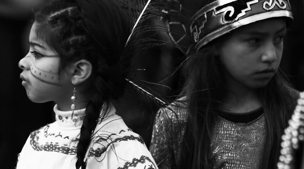 An image of two Native American children in their cultural garbs.