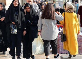 Veiled Iranian women pass by a bareheaded woman in Tehran on a street in Tehran