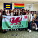 Image shows the Urdd delegation and the IHR team posing with a flag of Wales.