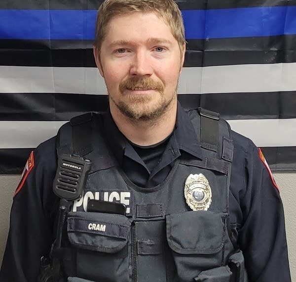 Police officer poses in front of a Blue Lives Matter flag