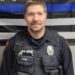 Police officer poses in front of a Blue Lives Matter flag