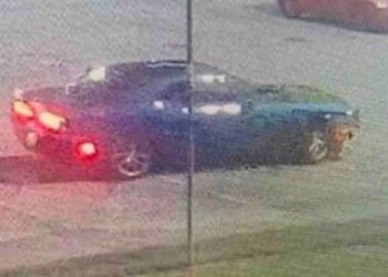 blue Dodge Challenger outside jail fence