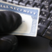 Gloved hand holding an obscured social security card