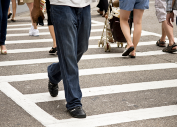 A large group of pedestrians in a large crosswalk.