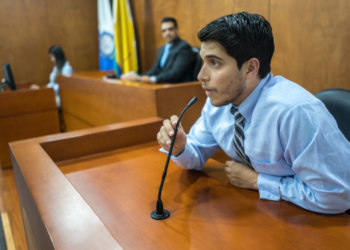 A well dressed business man testifying in a court of law.