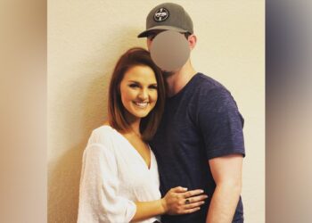 Woman and man wth baseball hat embrace in photo.
