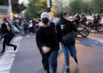 Blurred photo of two women running towards the camera as other people can be seen scattering