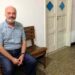 Carlos Luis Malatto sitting on a wooden bench in a house