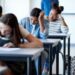 Young multi-ethnic female students writing exams