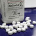 Alternate Text: Image of white OxyContin bottle with white pills laid out in front. Source: Flickr