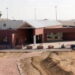 A slightly elevated shot of Florence Supermax prison, a red brick building surrounded by short grass and hills.