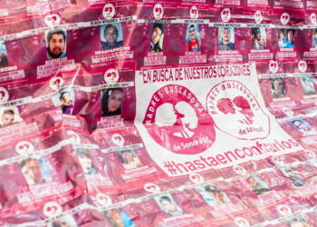 Image Description: A large pink banner with "En Busca De Nuestros Corazones" and "Madres Buscadores" written across the middle. There are many images of disappeared people. Source: https://www.flickr.com/photos/filguadalajara/53368996982/in/photolist-2pj34HD-2pj8EbH-2pja1kA-2pj34so-2pj34n8-2pj9iQb-2pja1gc-2pj34eC-2pja2pQ-2pj9ZZR-2pj9ZCt-2pj7GEv-2pj8Ept-2pj8EkA-2pj34Fu-2pj33ZQ-2pj8DJf-2pj9hM9-2pj34qz-2pja1rx-2hS7sD8-2nmdgdT-2pj8Dww-2nmdg8H-2nmdgpE-ULdzFe-UUkAHs-UXQmFc-TFsA3Q-TFswrS-UUkBAu-UXQnGF-UXQozT-TFsyG3-2nmdgiH-2nmdco6-ULdAX2-2nm7Utq-2nm7U3L-2nmdcJ6-2nmfHX7-2nmfHM2-2nm7UmM-ULdAcV-2nmeqmr