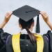 Rear view of young student wearing graduation gown with graduation cap in her commencement day.